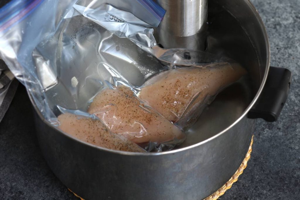 Sous vide cooking chicken breasts in warm water bath.