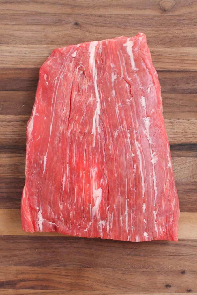 A piece of raw flank steak on the counter.