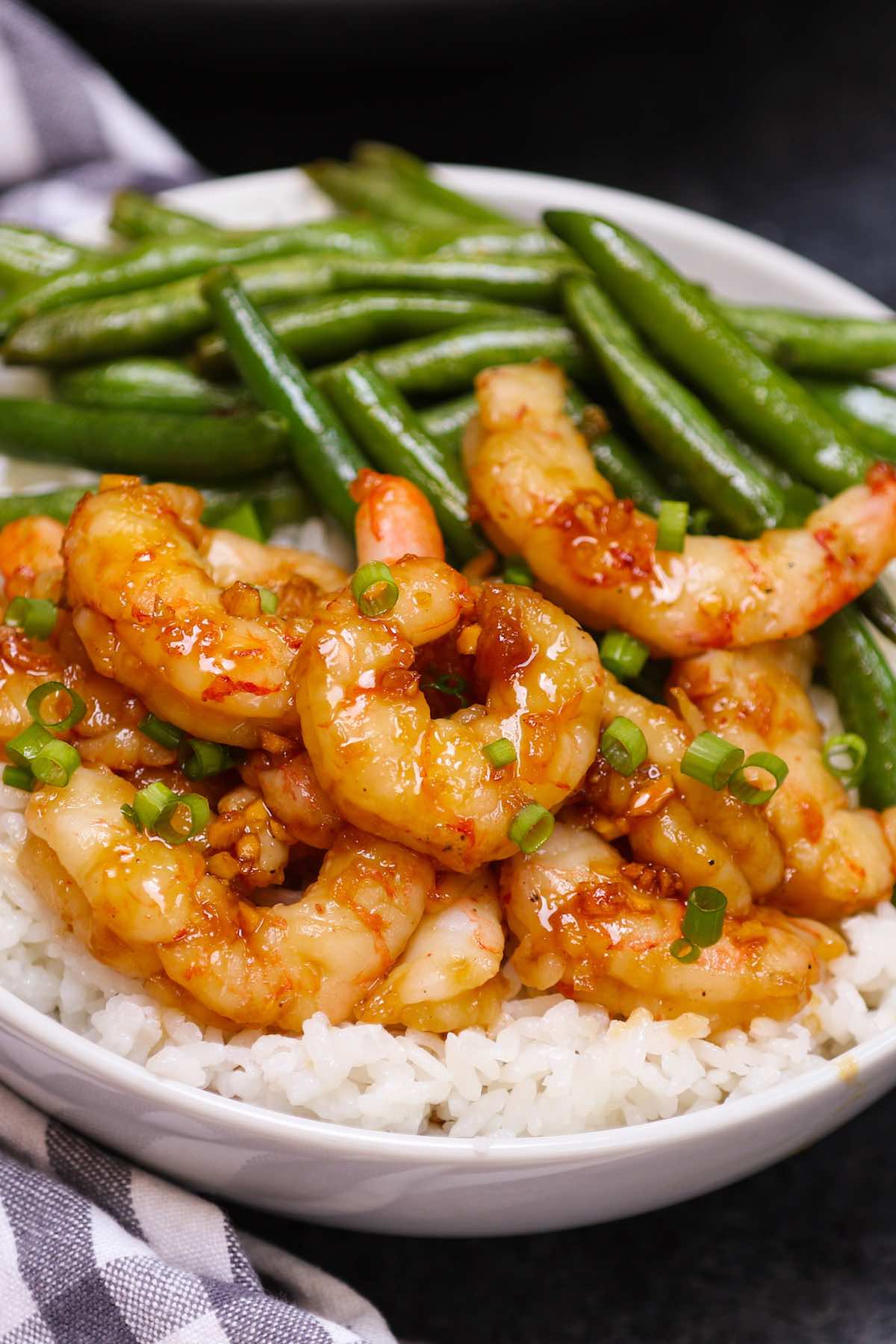 Sous vide honey garlic shrimp served with green beans over rice in a white bowl.