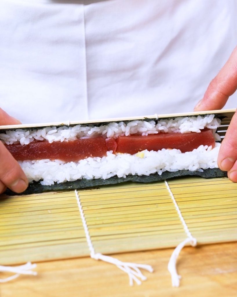 Closeup showing rolling tekkamaki using a bamboo mat.