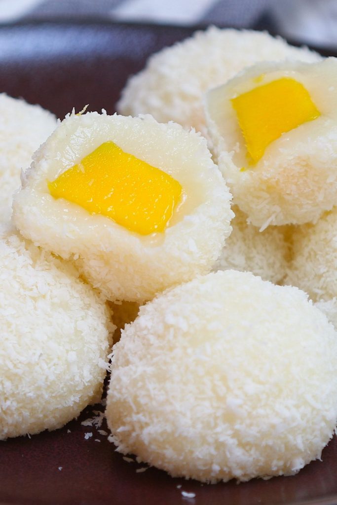 May I impress you with this refreshing homemade Japanese Mango Mochi? Tangy and sweet mango filling is covered with soft and chewy mochi cake. It’s rolled into mango mochi balls with a delicious shredded coconut coating, perfect for a hot summer day! This recipe is quick to make, and can be easily customized for vegan or dairy-free preferences. #MangoMochi
