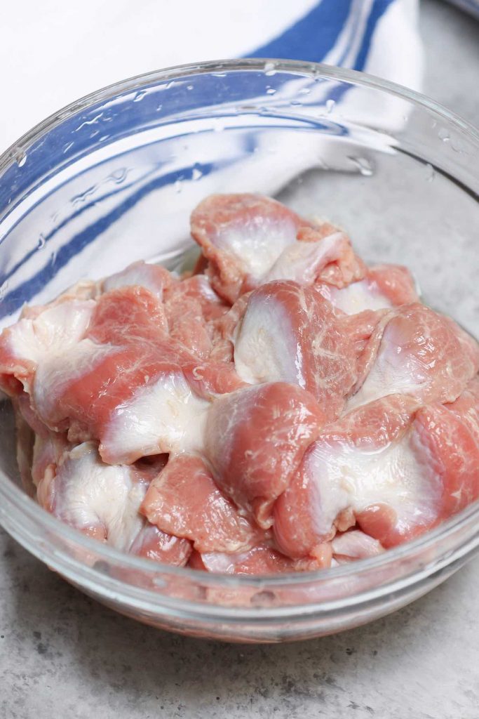 Raw chicken gizzards in a clear bowl.