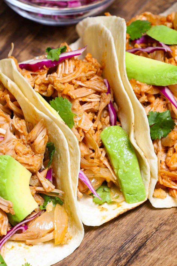 Cooked jackfruit served over tacos with shredded red cabbage, avocado, and cilantro.