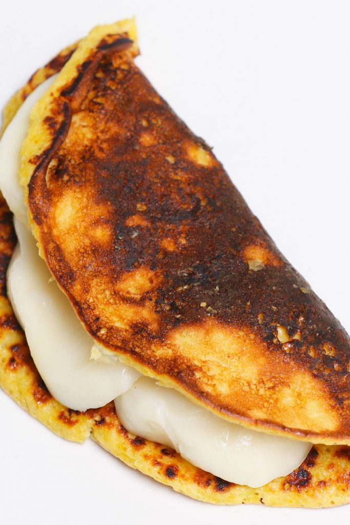 Cachapas are soft, sweet, and savory corn pancakes – a delicious Venezuelan breakfast dish. Made with fresh corn and a few other simple ingredients, these cachapas can be easily folded over a cheese filling such as Queso de Mano, mozzarella, or cream cheese. Incredibly delicious! (No special flour needed.) #cachapas