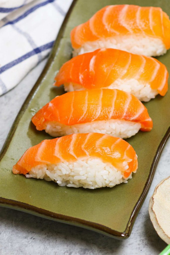 Salmon Nigiri made with sashimi-grade salmon with fluffy sushi rice! It’s so much cheaper than the restaurant, and incredibly easy to make at home. I’ll share with you the secrets to filet and cut salmon for nigiri sushi or sashimi with step by step photos and a video. #salmonNigiri #nigiriSushi