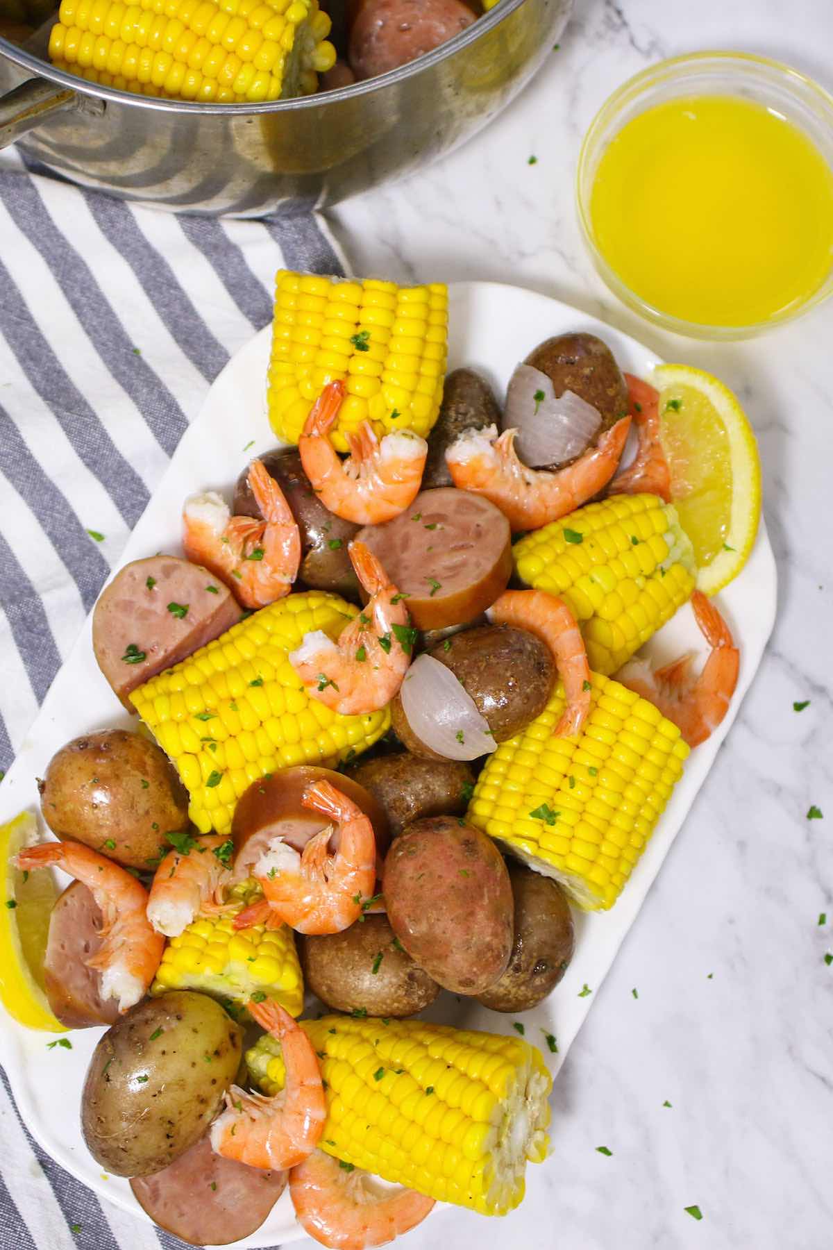 Low Country Boil is a Southern favorite that’s a great crowd pleaser! Tender shrimp are boiled with hearty potatoes, smoked sausage, sweet corn, and the delicious old bay seasoning. This easy one-pot meal is perfect for a party as well as a casual weeknight dinner! #LowCountryBoil #FrogmoreStew