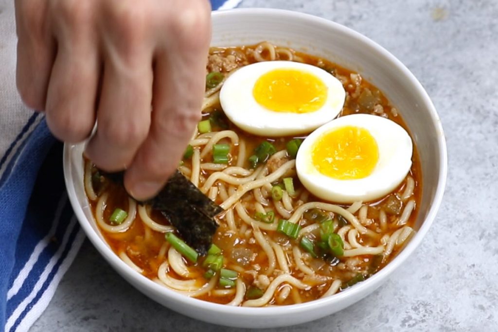 Photo showing adding toppings to the spicy ramen.