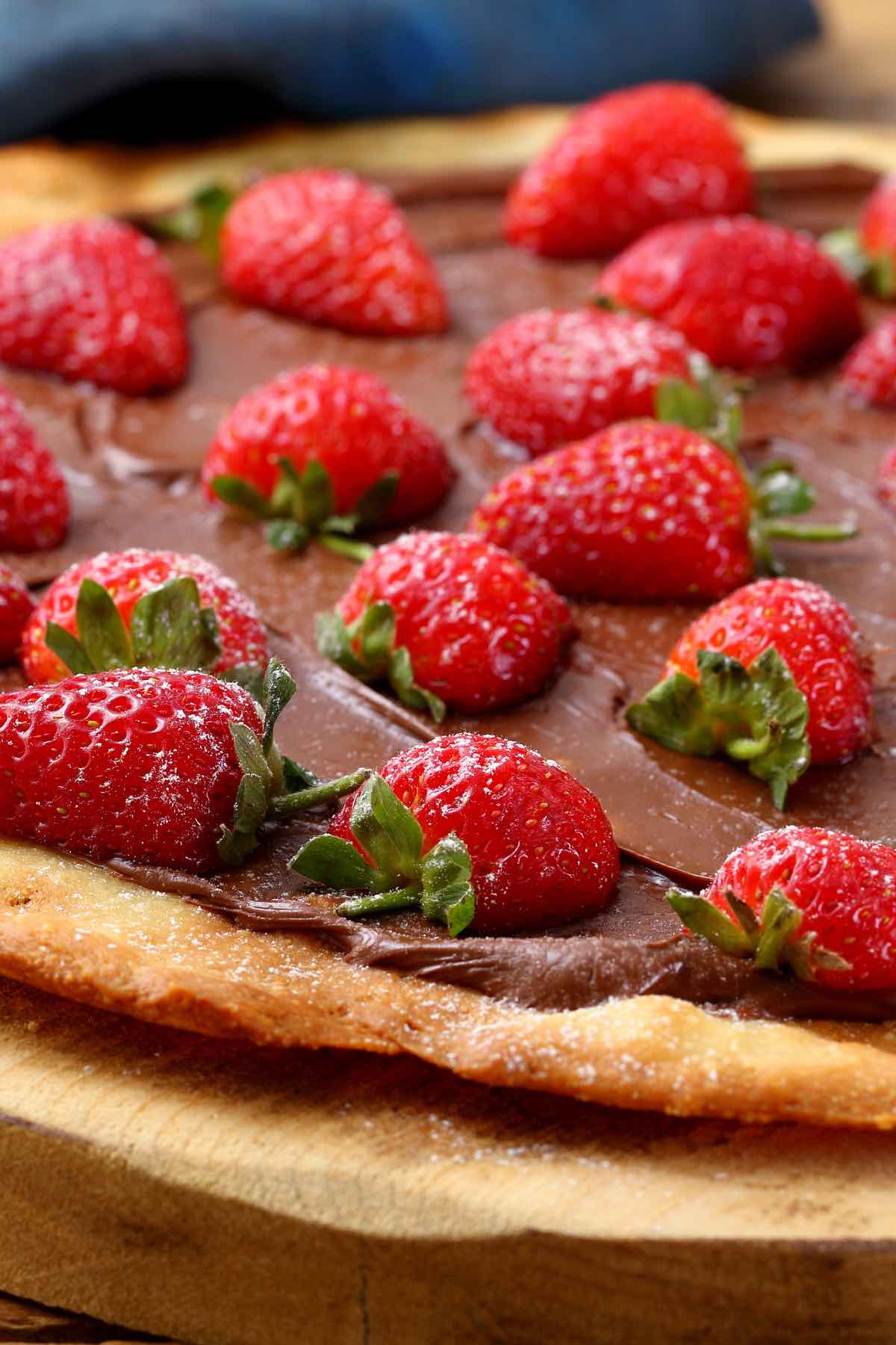 This Nutella Pizza is a must-try dessert that’s sure to impress your guest. It’s perfectly easy to make – this recipe skips out on the tomato and cheese in favor of adding chocolate spread onto the pizza crust, making a mouth-watering dessert. You can easily customize it with different topping ideas like strawberries, bananas, or marshmallows.  
