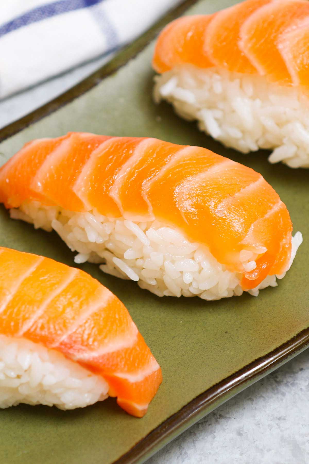 An easy and complete homemade Nigiri tutorial with lots of tips and tricks. Unlike maki sushi, nigiri isn’t rolled. Instead, it’s comprised of a thin slice of raw or cooked seafood like salmon or shrimp atop a mound of vinegary rice. You’ll learn everything about Japanese nigiri including the difference between nigiri and sashimi, and how to make perfect nigiri at home. 