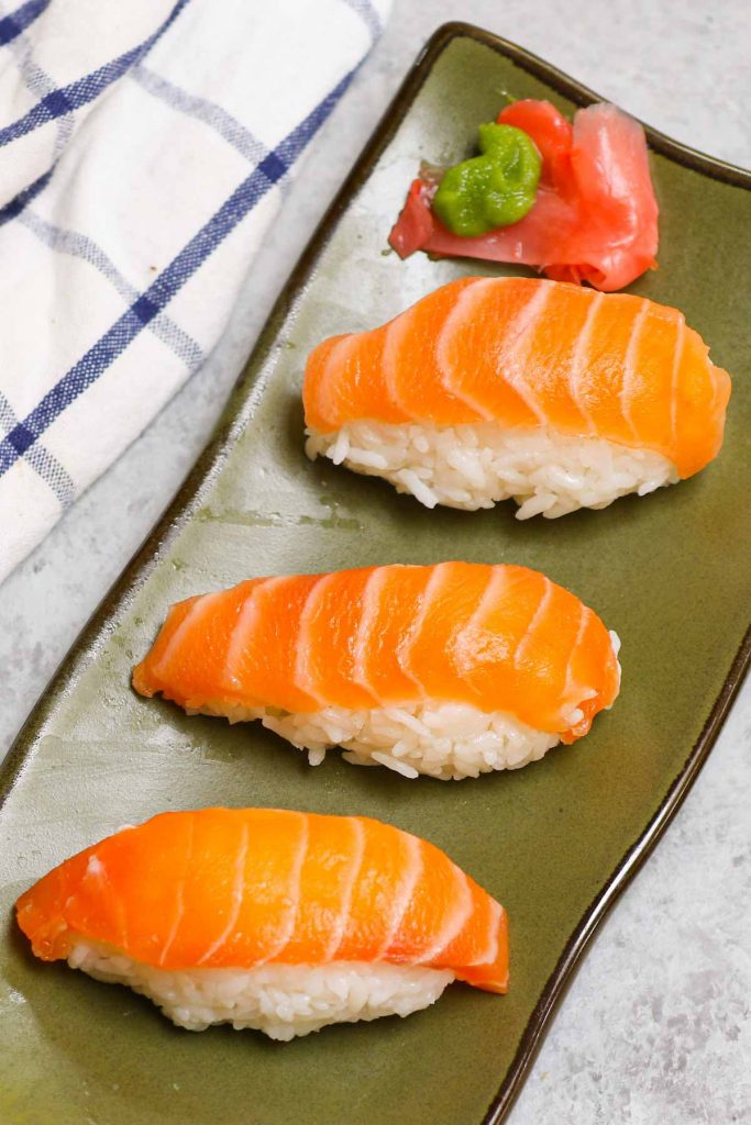 An easy and complete homemade Nigiri tutorial with lots of tips and tricks. Unlike maki sushi, nigiri isn’t rolled. Instead, it’s comprised of a thin slice of raw or cooked seafood like salmon or shrimp atop a mound of vinegary rice. You’ll learn everything about Japanese nigiri including the difference between nigiri and sashimi, and how to make perfect nigiri at home