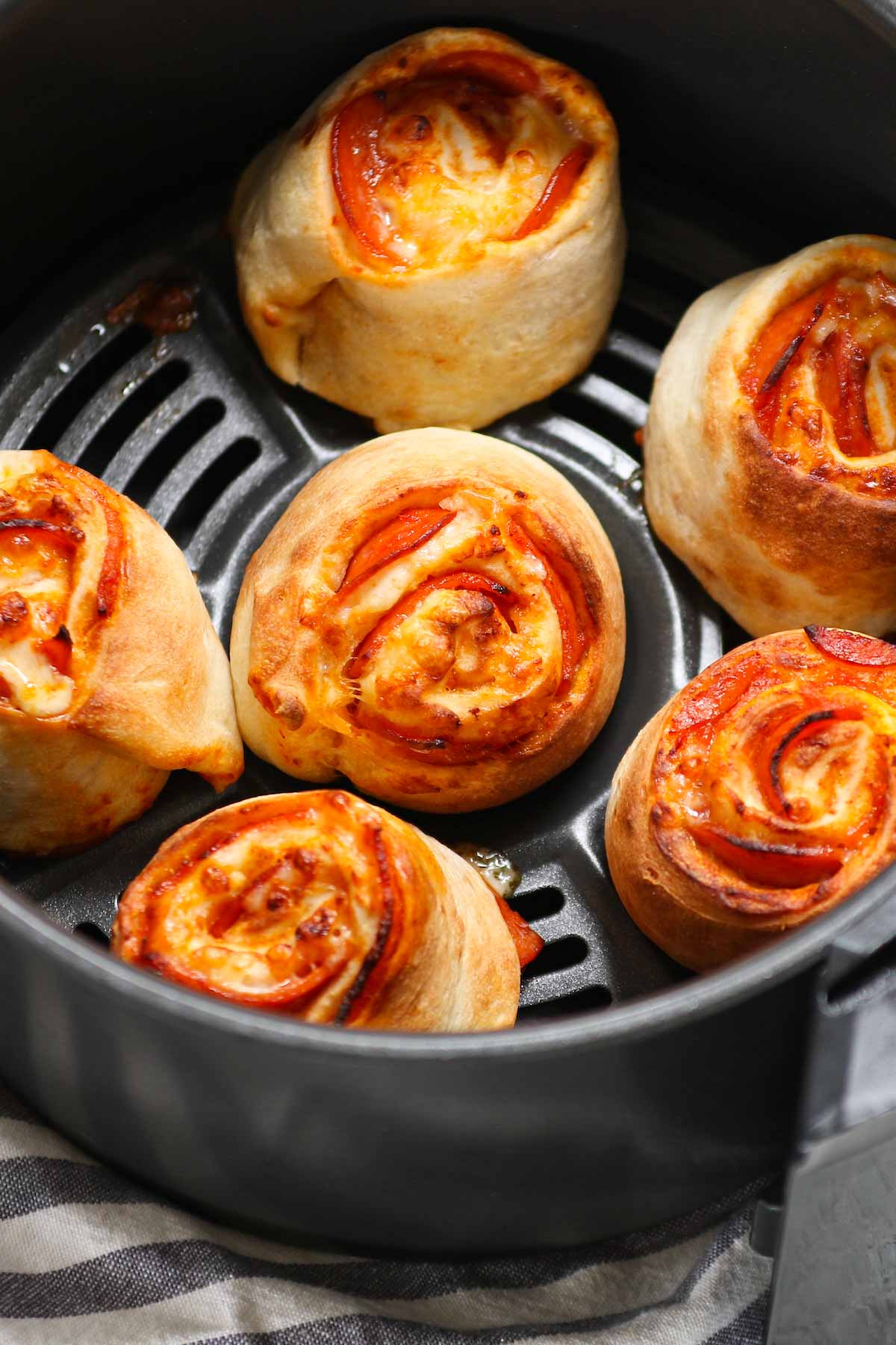 These Air Fryer Pizza Rolls have delicious pepperoni and mozzarella cheese packed in pizza pockets – an instant crowd-pleaser great for appetizer or snack. You can easily make these bite-sized mini pizzas at home from scratch in under 10 minutes. We’ve also included instructions on how to air fry frozen pizza puffs straight from the freezer. 
