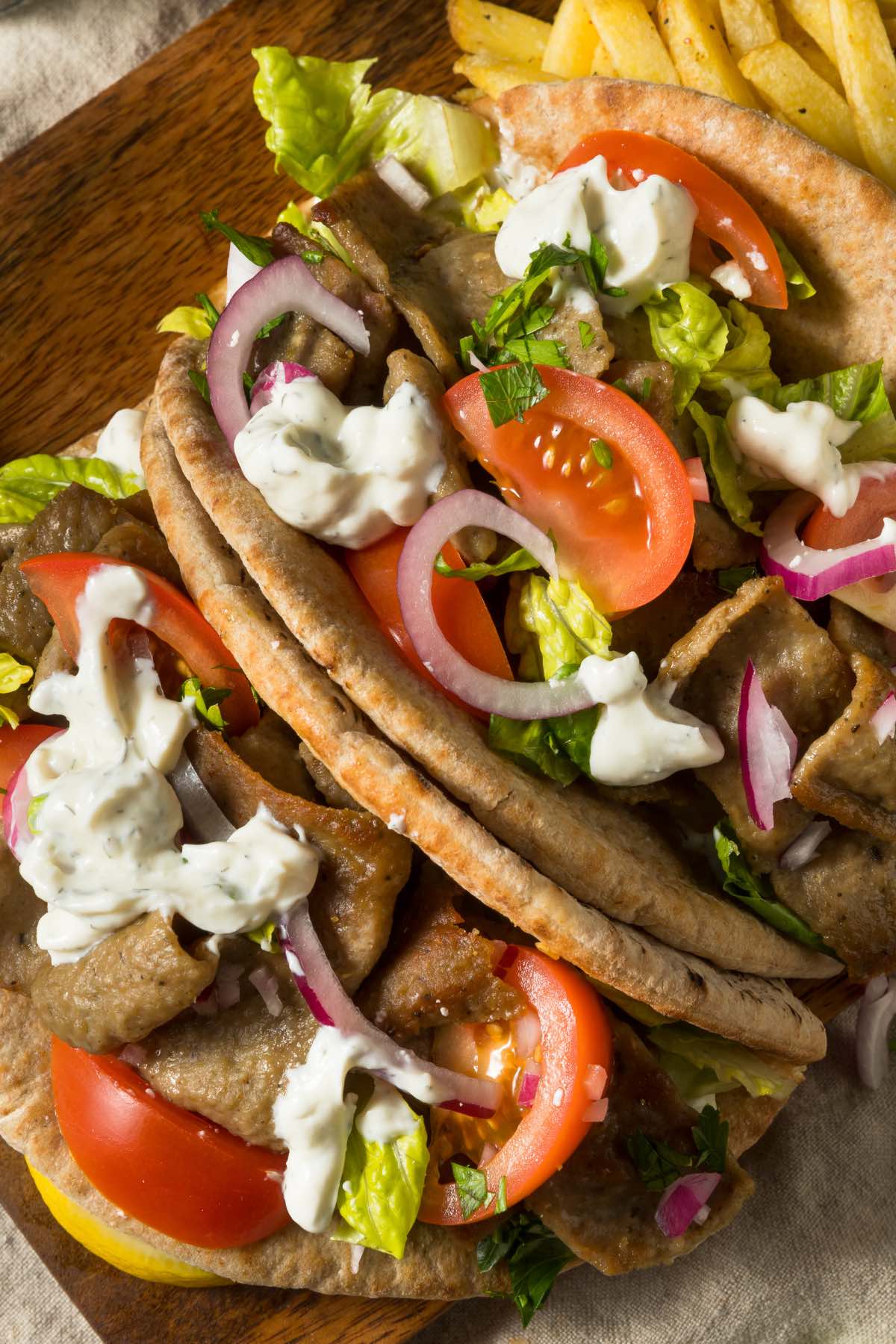 The Easy Greek Gyro Sandwich is gyro meat, fresh vegetables, and feta cheese wrapped in warm pita bread. You can top it with Tzatziki sauce, and it's the ultimate sandwich for Greek food lovers!