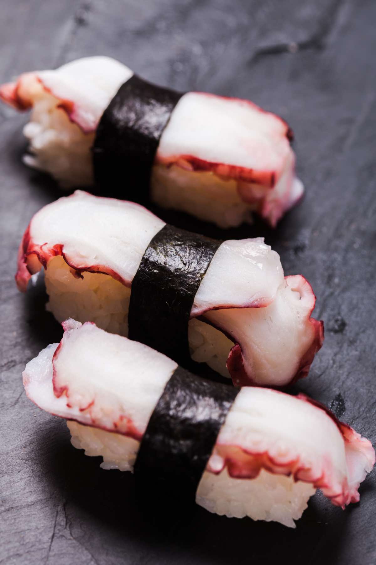 Japanese Octopus Sushi, or Tako nigiri is a traditional Japanese sushi roll that consists of a small ball of seasoned sushi rice topped with slices of sashimi-grade octopus. The rice and octopus are held together by a thin strip of nori