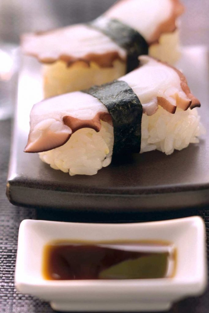 Japanese Octopus Sushi, or Tako nigiri is a traditional Japanese sushi roll that consists of a small ball of seasoned sushi rice topped with slices of sashimi-grade octopus. The rice and octopus are held together by a thin strip of nori