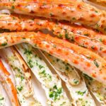 Garlic butter crab legs with parsley on a white plate