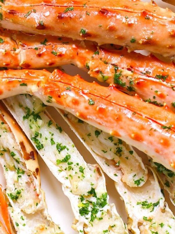 Garlic butter crab legs with parsley on a white plate
