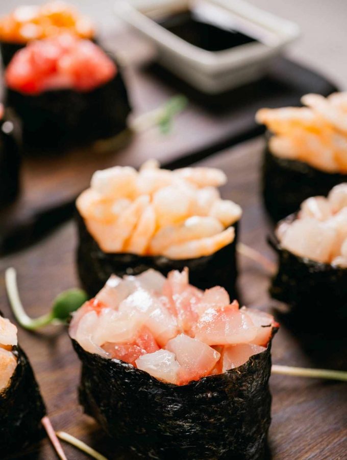 Gunkan Sushi is a ship-like sushi roll in the shape of an oval, consisting of a nori seaweed sheet wrapped around a ball of rice with dressing at the very top. Some common toppings include flying fish, salmon or sea urchin roe.