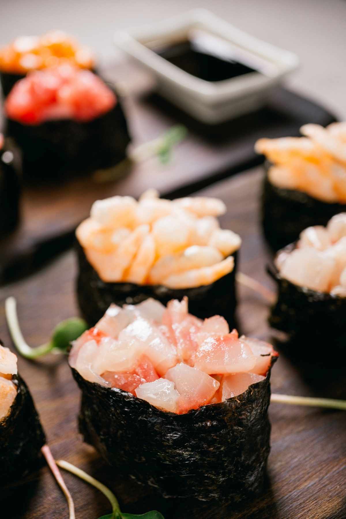 Gunkan Sushi is a ship-like sushi roll in the shape of an oval, consisting of a nori seaweed sheet wrapped around a ball of rice with dressing at the very top. Some common toppings include flying fish, salmon or sea urchin roe.