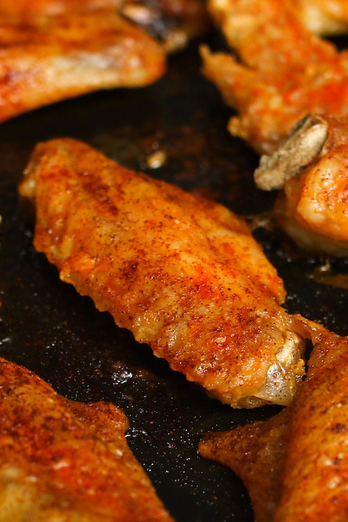 Close-up of crispy seasoned baked chicken wings on a baking pan