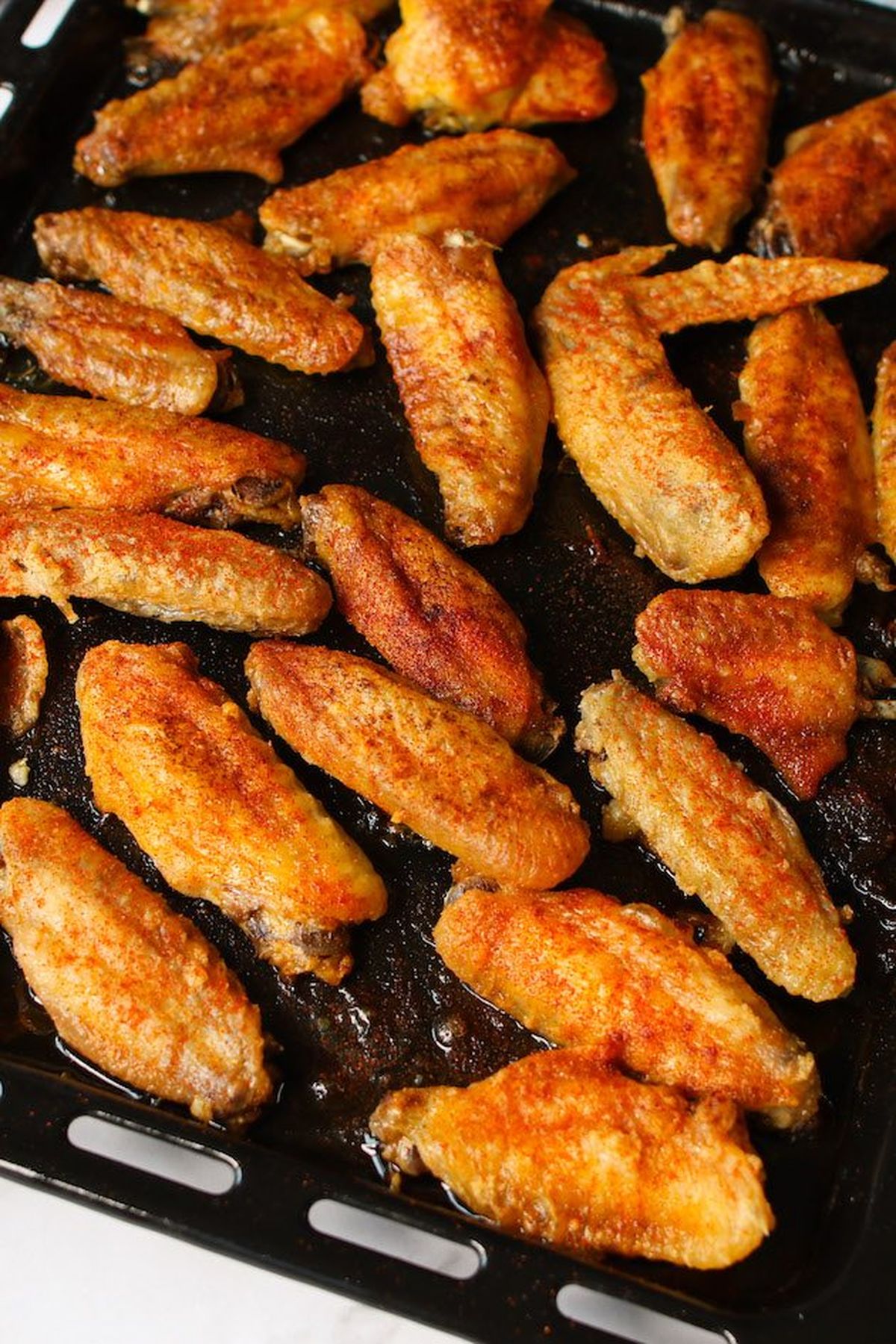 Crispy baked chicken wings seasoned with spices on a baking tray