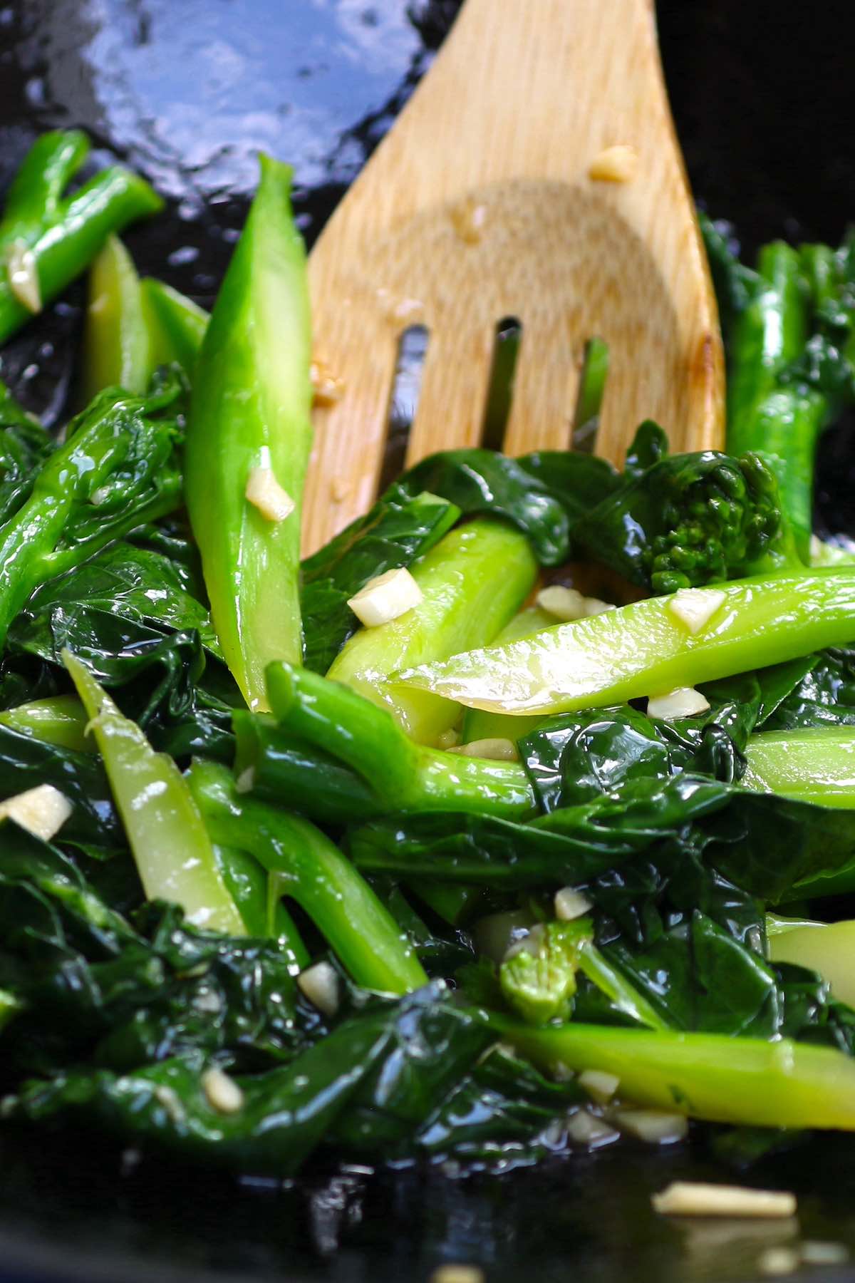 Chinese broccoli stir fry with gai lan in garlic sauce on a white oval plate with chopsticks