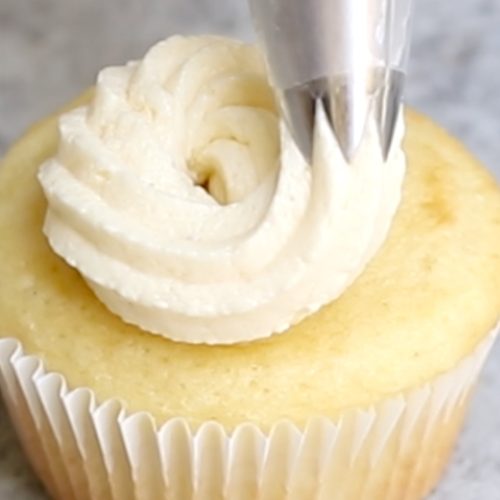 Close-up showing piping the frosting onto a cupcake