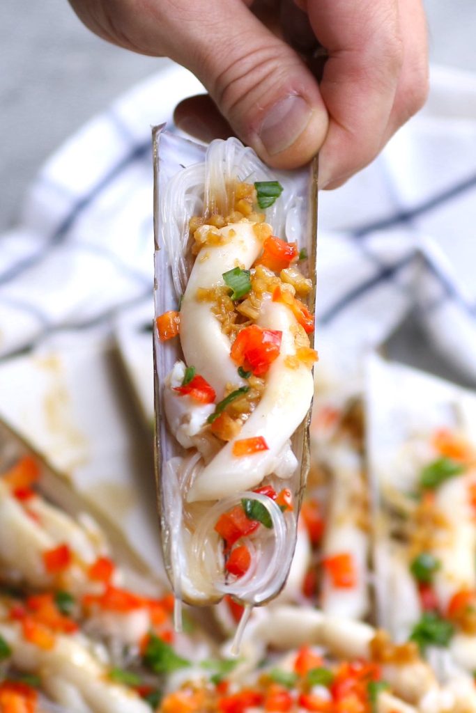 Close of holding cooked razor clams in their shells