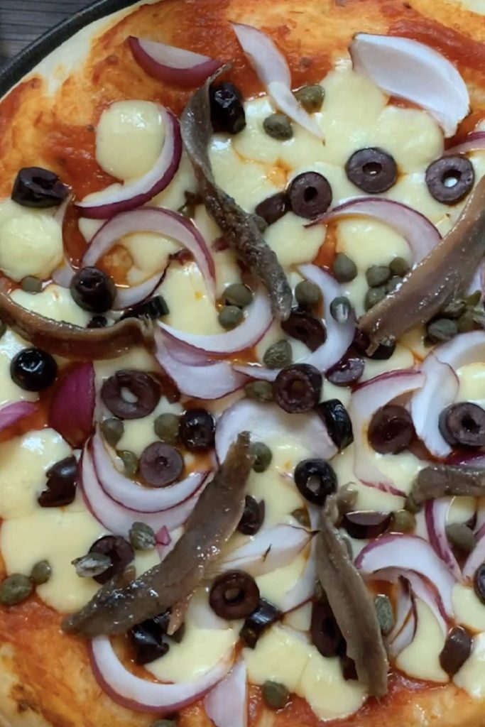Add anchovies to the par-baked pizza