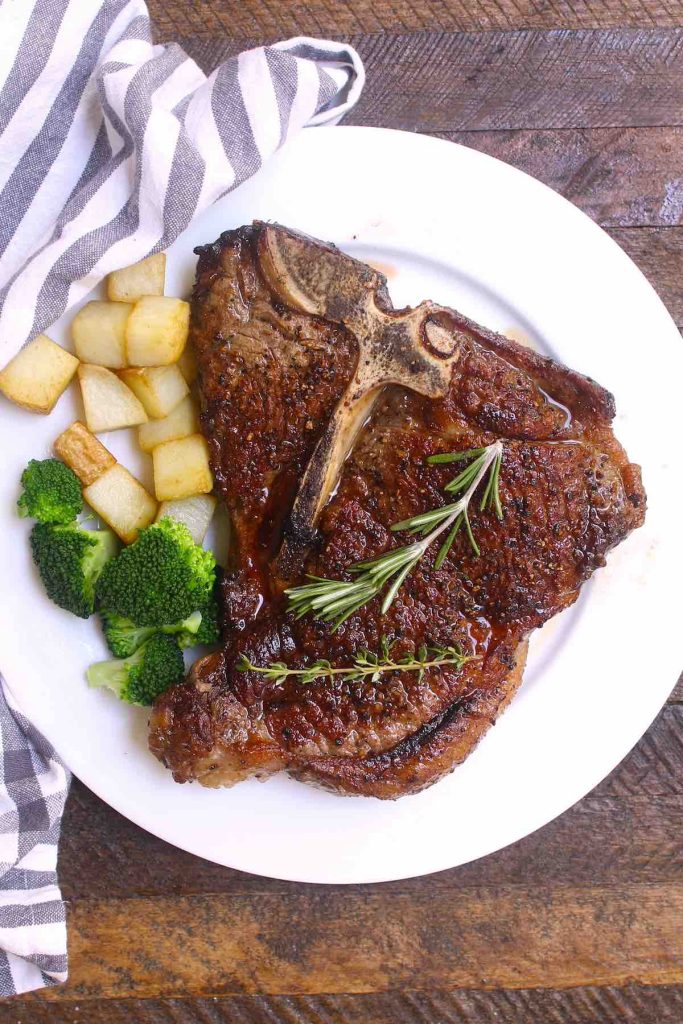 Baked T-bone steak served with potatoes and broccoli on a plate