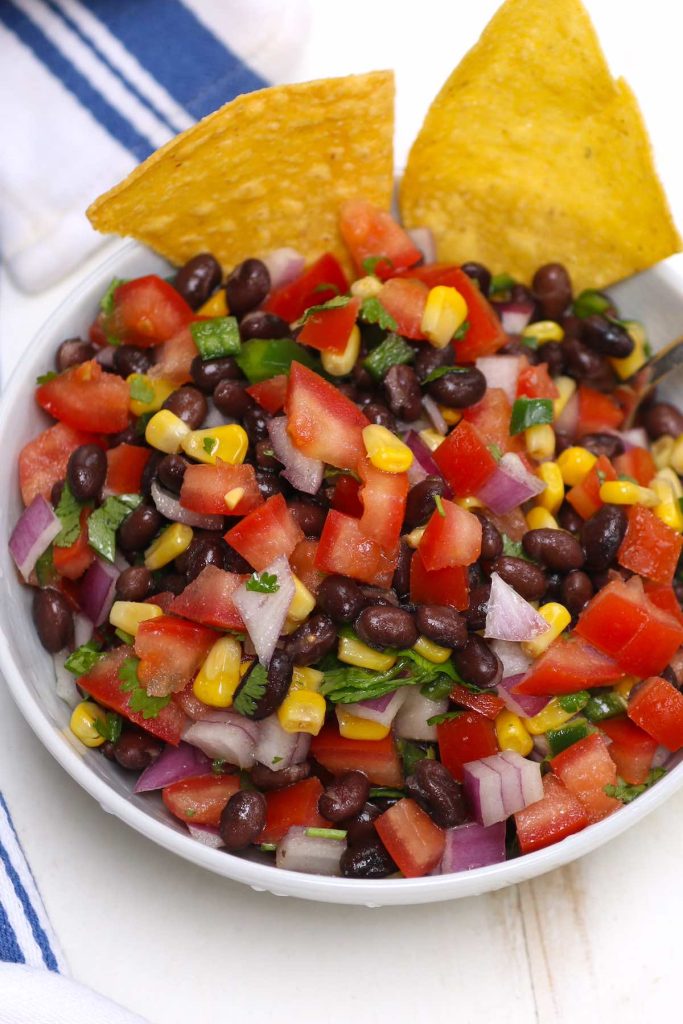 Colorful and refreshing black bean and corn salsa served with tortilla chips in a bowl