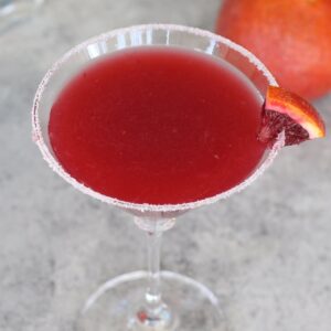 Cocktail recipes &ndash; blood orange margarita in a sugar-rimmed martini glass garnished with an orange slice