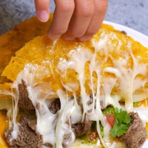 Mexican recipes &ndash; cheesy steak mulitas with stretchy melted cheese, beef, guacamole, and cilantro being pulled apart