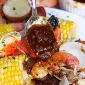 Seafood recipes &ndash; Cajun seafood boil with crab, shrimp, clams, corn, and spicy butter sauce being spooned over