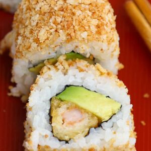 Sushi recipes &ndash; crunchy roll sushi with crispy panko coating, shrimp tempura, and avocado on a red plate with chopsticks