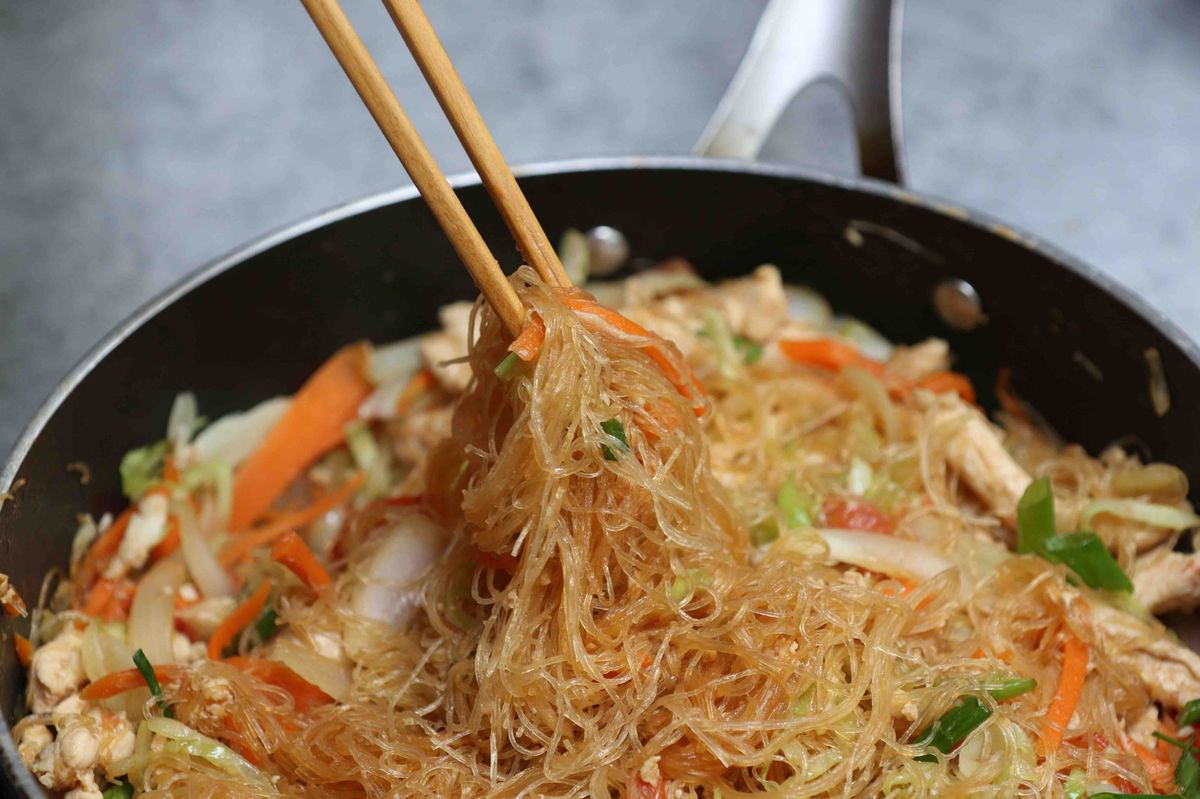 glass noodle stir fry with chicken, cabbage and carrots cooking in a wok