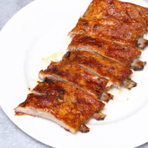 Sliced baked pork ribs on a white plate showing tender meat and caramelized crust