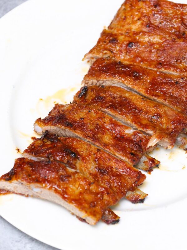 Sliced baked pork ribs on a white plate showing tender meat and caramelized crust