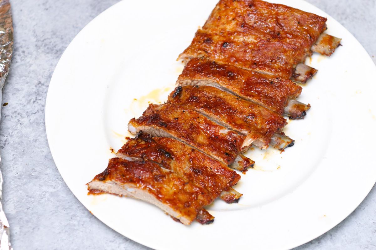 Sliced baked pork ribs on a white plate showing tender meat and caramelized crust