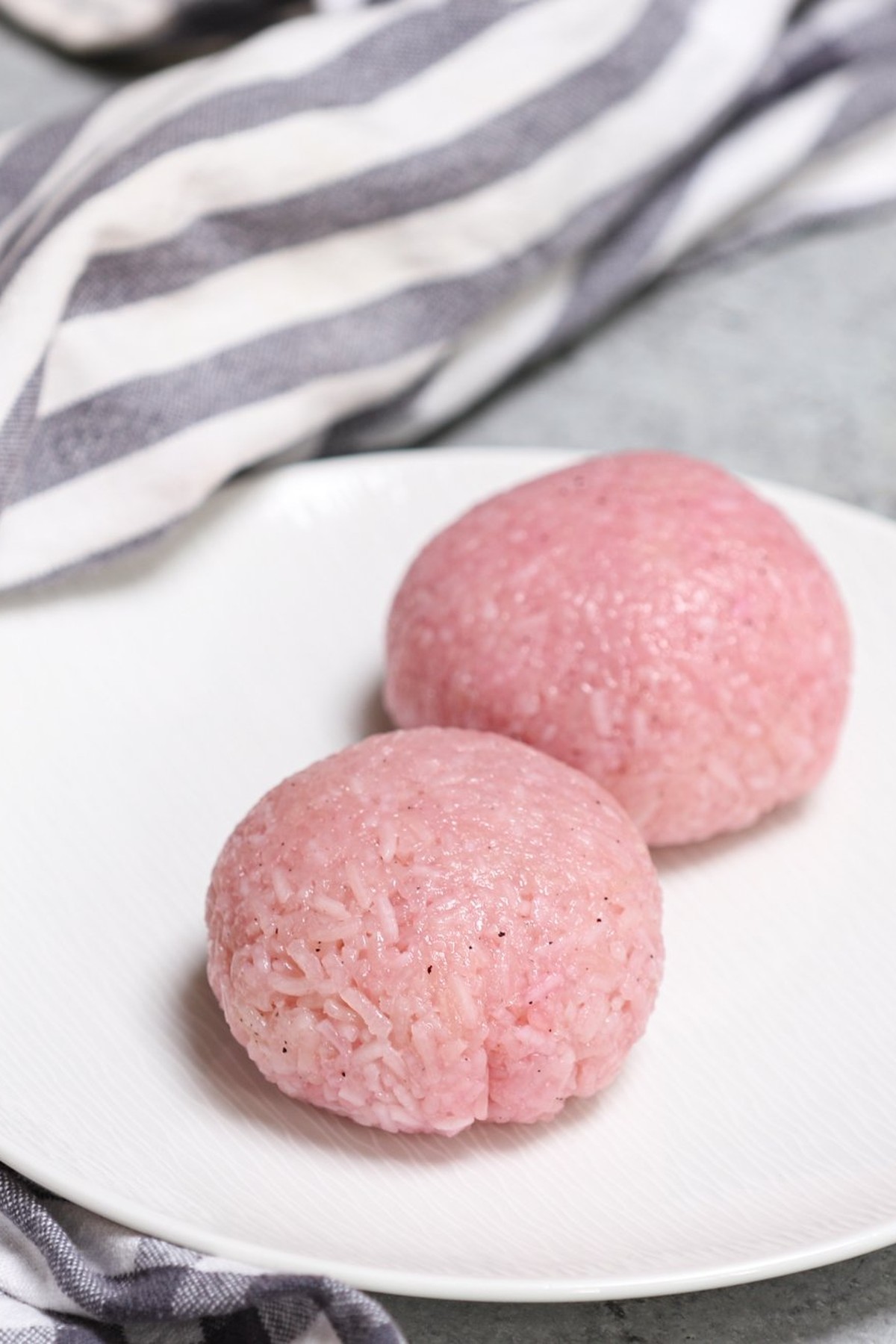 Two pieces of pink sakura mochi served on a plate